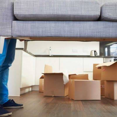 image of a couch being moved and feet of a mover and boxes in the background